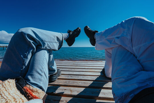 Low angle view of man and woman relaxing on a wooden deck by the sea