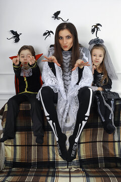 Happy family with children in costumes of witch and vampire in a house in holiday Halloween