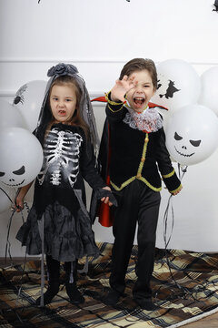 Happy family with children in costumes of witch and vampire in a house in holiday Halloween