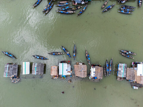 Aerial view of Kalabagi village with traditional wooden boats moored near stilted houses on the river in Khulna District, Khulna Division, Bangladesh.