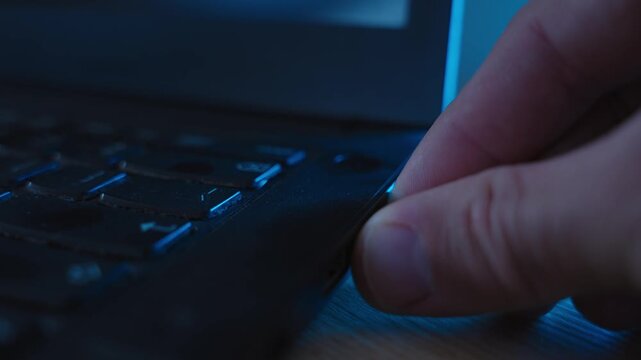 Flash drive being plugged into laptop computer by spy or hacker in dark room. Suspicious activity hacking system or server. Person stealing information and sensitive data or installing spyware app