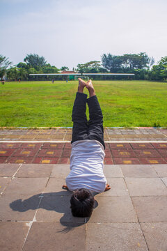 Unrecognizable people, teenage boys doing freestyle somersaults in the park.