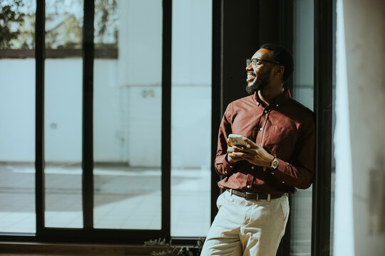 Man enjoying sunlight while using smartphone in a stylish interior space
