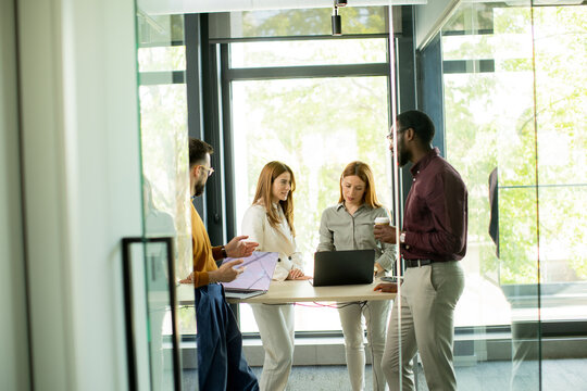 Group of four people discuss ideas in office during daytime in a modern workspace