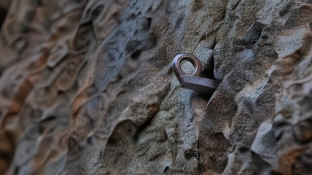 piton. Close-up of a rugged rock wall with a single metal piton as focal point. lifestyle magazines, social media lookbooks, designed for lifestyle magazines and social media content.