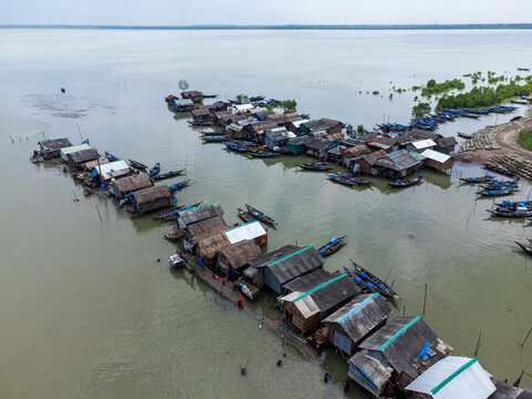 Aerial view of Kalabagi village with stilt houses and numerous wooden fishing boats moored along the riverbank in Khulna District, Khulna Division, Bangladesh.