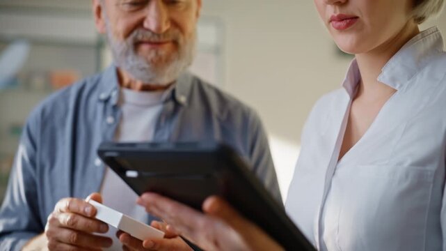 Doctor hands typing tablet choosing medicine for senior customer indoors closeup