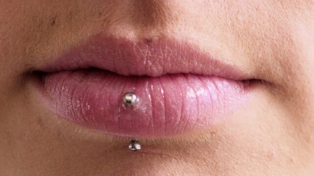 Mouth, closeup and smile with piercing in lips, skin or pride with metal bar for style expression. Woman, steel stud and beauty with cosmetics, confident or aesthetic with transformation for body art