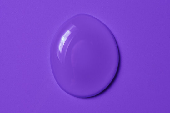 A transparent cosmetic product on a purple background.