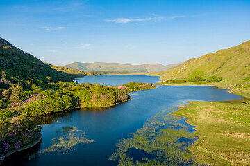 Obraz premium Pollacappul Lough near Kylemore Abbey glows in evening light beneath the mountains of Connemara, County Galway. A scenic travel landscape about lakes, valleys, and the Wild Atlantic Way.