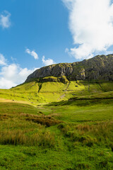 Naklejka premium Gleniff Horseshoe in County Sligo, Ireland, with rolling grassland beneath steep limestone mountains and bright clouds. A scenic drive through one of Irelands classic valleys.