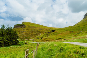 Naklejka premium Gleniff Horseshoe in County Sligo, Ireland, with rolling grassland beneath steep limestone mountains and bright clouds. A scenic drive through one of Irelands classic valleys.