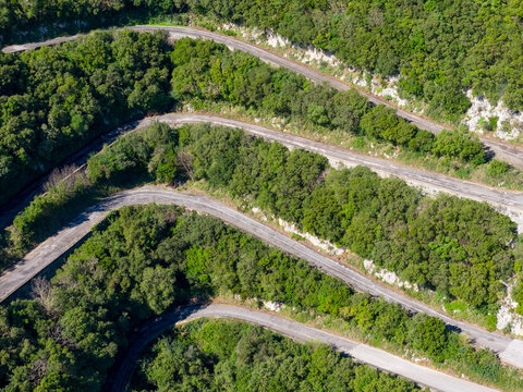 Steep mountain switchbacks and serpentine road winding through Mediterranean forest in Sokraki, Corfu, Greece