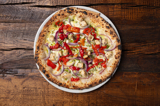 Vegetarian pizza with red peppers and red onion on rustic wooden table, overhead top view of freshly baked artisan pizza