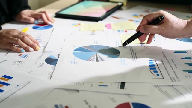 Professional business data analysis with financial charts, corporate team reviewing marketing reports and statistics, hands pointing at pie charts