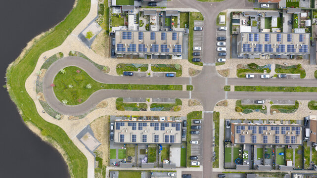 Aerial view of the Nobelhorst neighborhood featuring modern houses with solar panels on rooftops and symmetrical streets next to a canal in Almere, Flevoland, Netherlands.