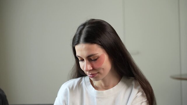 Close up of young woman applying hydrogel under eye patches during skincare routine at home. Beauty and self care concept with moisturizing eye masks, facial treatment, healthy glowing skin and