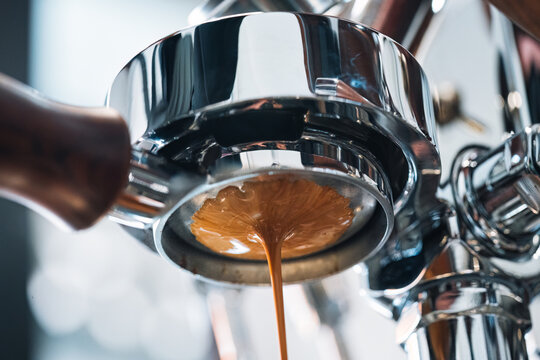 Espresso coffee pouring from bottomless portafilter at coffee maker