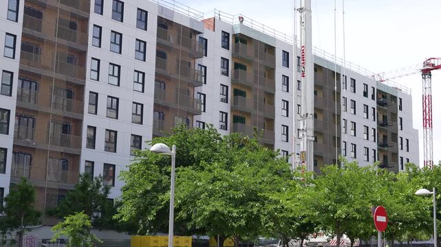 Madrid, Spain - May 12, 2026: Construction crane operating beside a residential apartment building under development in Valdebebas urban expansion district. Editorial.