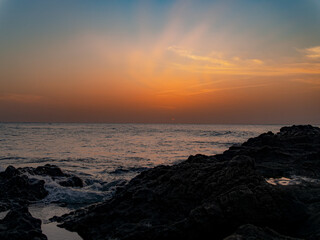 Fototapeta premium Ocean waves crashing on rocks during sunset