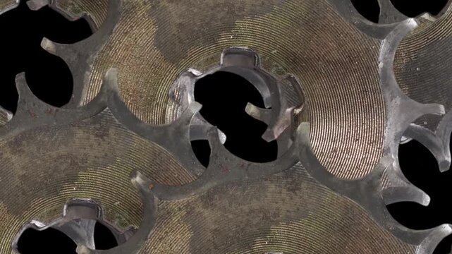 A metal disc rotates in a time-lapse sequence, revealing an intricate cut-out geometric pattern as it spins.