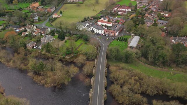 Croft-on-Tees UK: 21st Feb 2026: Drone view captures Croft-on-Tees. The scene shows houses, a river, fields, and bridge. Green trees and open spaces surround the area