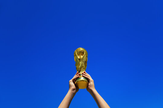 01.05.26. Frankfurt am Main, Hesse, Germany. A hands lifts the World Cup Trophy above, isolated against a blue summer sky. A Celebration or win of Football.