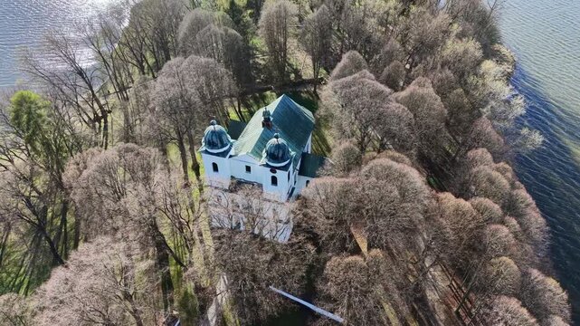 Stunning aerial perspective orbiting the historic Church of the Exaltation of the Holy Cross on Slanica Art Island in the Orava Reservoir, Slovakia