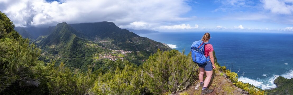 Hiker on the ridge of Pico do Alto, view over coastal landscape and steep cliffs, Madeira, Portugal
