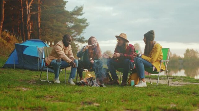 Friends sharing stories, Evening camping adventure sharing tales and enjoying warmth beside peaceful lakeside