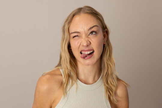 Female making playful face while posing in studio with ribbed sleeveless top and hoop earring