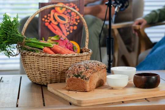 Seeded multigrain loaf resting on wooden cutting board on slatted table, wicker basket nearby