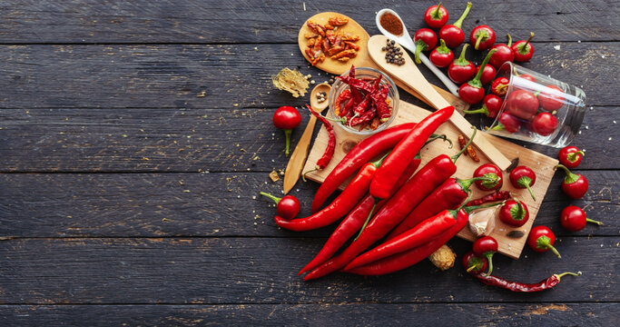 Vibrant red chili peppers on rustic wooden board with spices and garlic