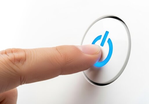 Finger pressing a modern power button on a sleek device isolated on white background