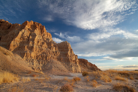 Golden evening light illuminates dramatic eroded cliffs and desert terrain at Cathedral Gorge State Park in eastern Nevada.
