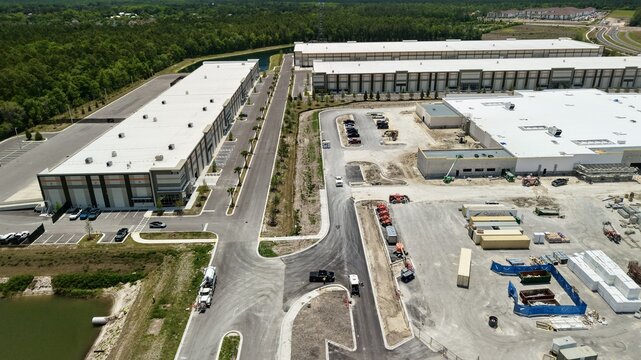 Aerial view of the large warehouse complex and construction site at Saint Johns Parkway and International Golf Parkway with lush forest World Golf Village, Florida, United States.