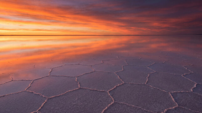 Vibrant sunset reflection on tessellated salt flats with geometric patterns