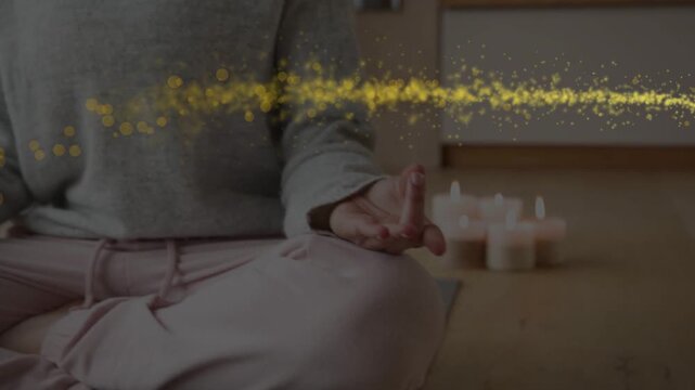 Woman meditating for wellness, camera pulling back showing candles, golden swirl circling hands