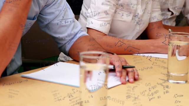 Lecture starting having three seated adults writing notes, moving pens, recording table equations