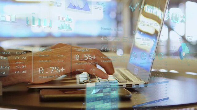 Mature man placing hands on laptop keys and typing at table, finance charts updating for analysis