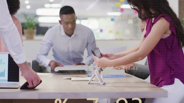 Woman reaching for paper small team gathering around tablet animated charts guiding business plans