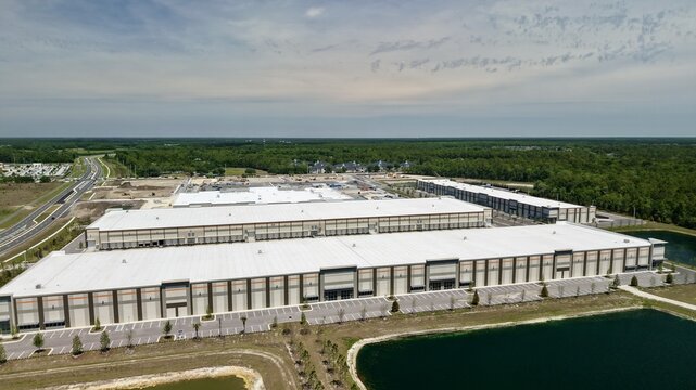 Aerial view of large industrial warehouses and distribution centers with loading docks and parking lots near Saint Johns Parkway World Golf Village, Florida, United States.