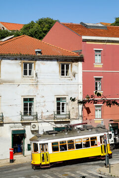 Iconic yellow Tram 28 passing historic Lisbon facades