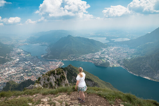 Female Hiker admiring panoramic views over Lake Como and Lecco from mountain viewpoint, ideal for travel
