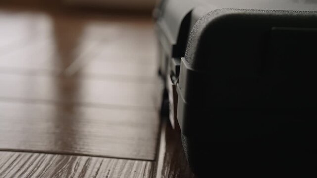 Worker hand unlocking small padlock and opening black plastic case containing cordless drill and other equipment, revealing tools needed for repair or construction project, close-up, slow motion.