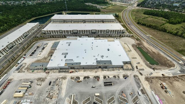 Aerial view of large industrial warehouses and construction site at Foundry Lane with white rooftops and surrounding greenery World Golf Village, Florida, United States.