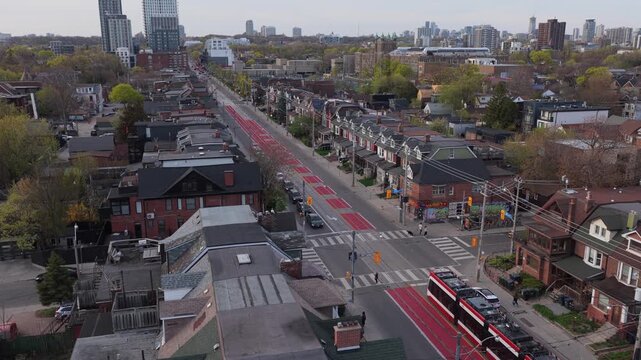 Aerial shot of TTC streetcar traveling on North American street, urban landscape with residential homes, downtown core and modern public transportation
