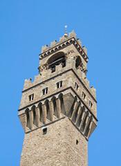 Obraz premium Arnolfo Tower of Palazzo Vecchio medieval battlements and stone masonry Against Blue Sky in Florence