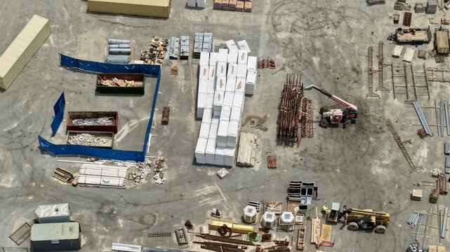 Aerial view of the construction staging area at Foundry Lane with stacks of building materials, shipping containers, and heavy machinery in World Golf Village, Florida, United States.