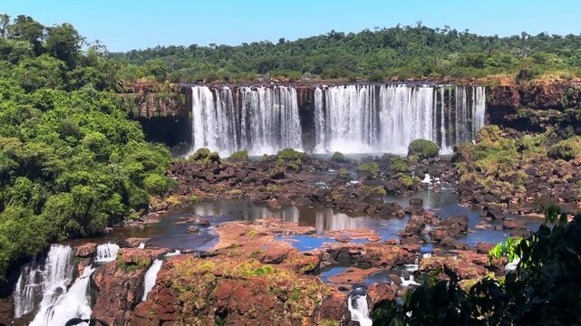 Panoramic view of the majestic Iguacu Falls in Brazil, a stunning natural wonder with cascading water over rocky cliffs surrounded by lush tropical rainforest